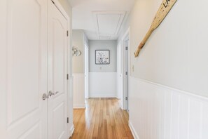 Un pasillo con puertas blancas, suelo de madera y un cuadro en la pared.