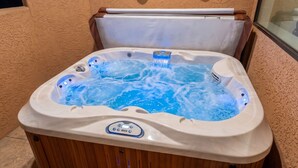 Un jacuzzi con panel de control, base de madera y tapa blanca.