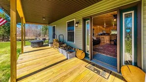 A covered porch with a wooden deck, a fire pit, and a seating area. - Charming All Wood InteriorAdirondak Cottage (Malone)