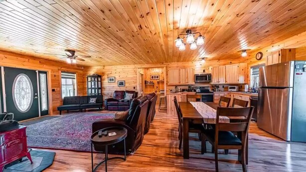 A spacious log cabin interior with a dining area, kitchen, and living room. - Charming All Wood InteriorAdirondak Cottage (Malone)