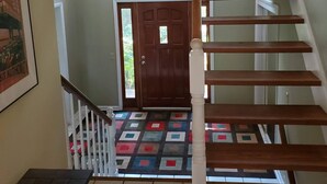 A staircase with wooden steps and white railings, leading to a door with a colorful mat. - Large Home close to everything, Dogs welcome. (Fitchburg)