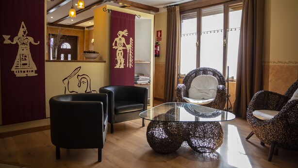 Uma sala de estar moderna com uma mesa de centro de vidro, cadeiras de palha e couro preto, e uma cortina vermelha com padrão branco.