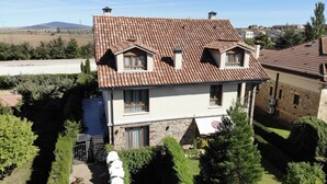 Uma casa de dois andares com telhado de telhas, paredes de pedra e um pequeno jardim.