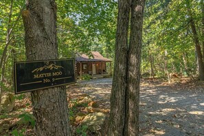 A wooden cabin labeled 'Mattie Moo No. 9' surrounded by trees.