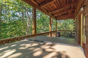 Una terrazza esterna coperta con ringhiera in legno, un tavolo in metallo e una sedia.
