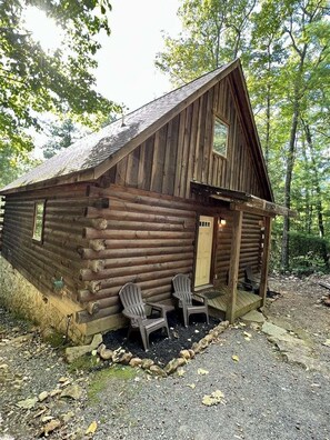 En rustik timmerstuga med en veranda och två Adirondack-stolar.