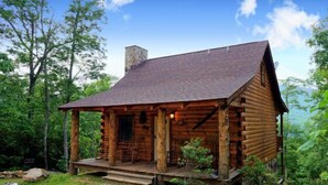 Un rustico chalet di legno con veranda, camino e vista panoramica sulla foresta circostante.