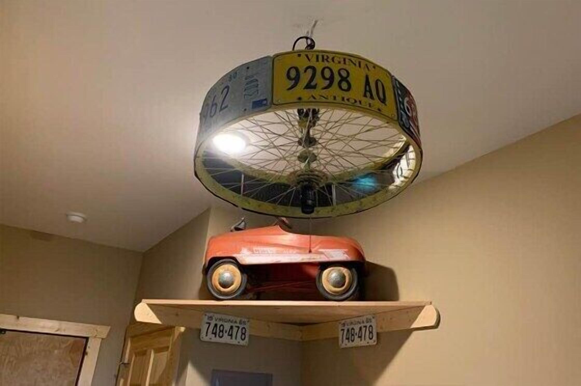 A ceiling fan with a circular light fixture and a vintage car model on a shelf below.