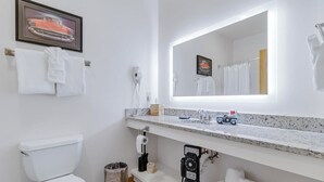 Un bagno con il water, un lavabo con specchio, un asciugacapelli e un cestino.
