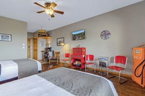A hotel room with two beds, a ceiling fan, a red toolbox, and a Gulf gas pump.