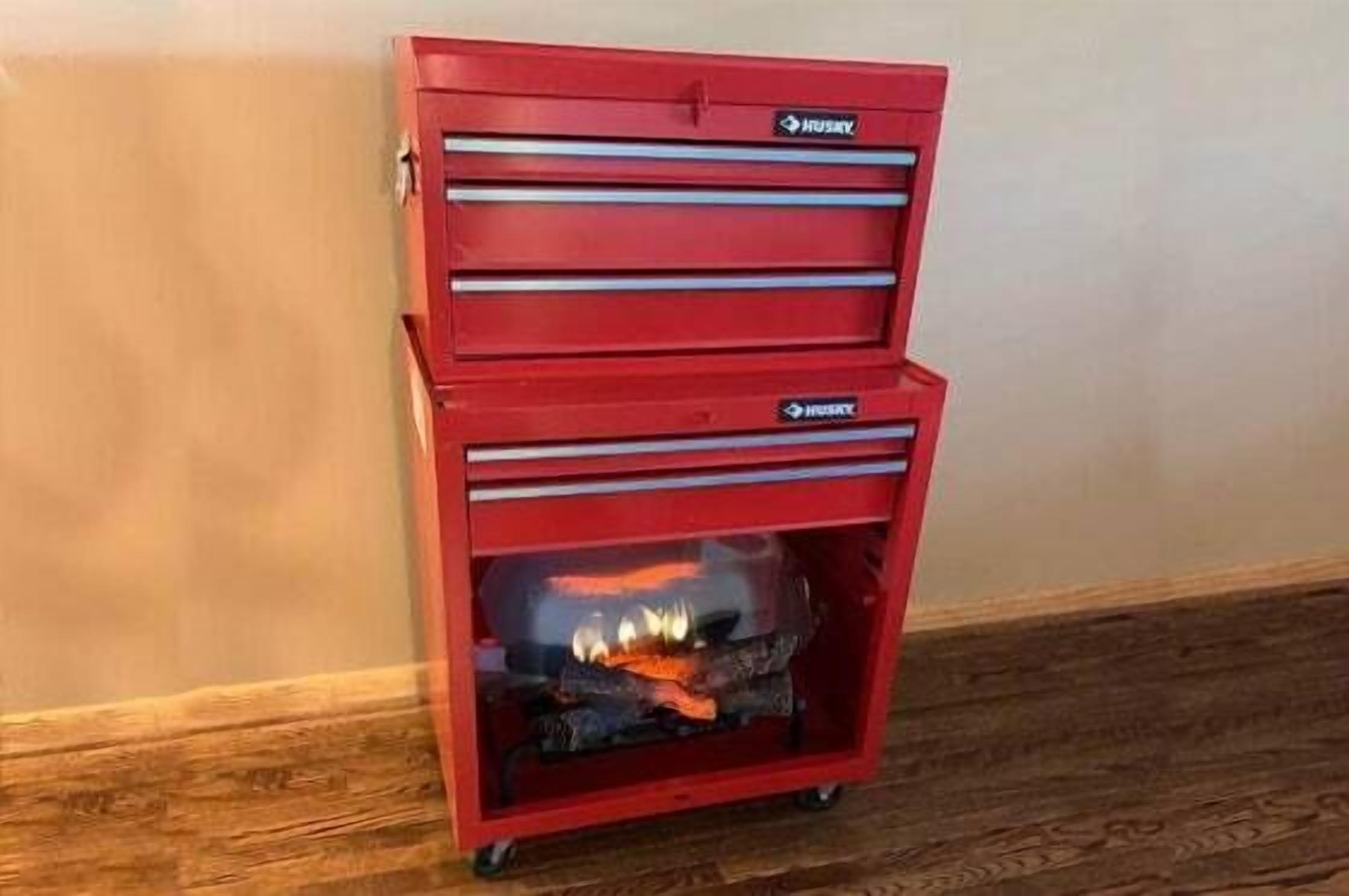 A red storage cabinet with multiple drawers and a glass front, against a plain wall.