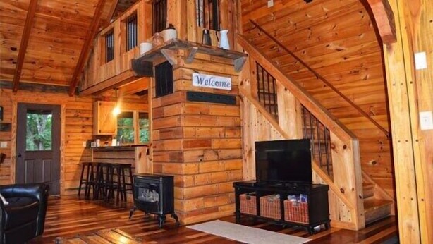 Een houten chalet interieur met een trap, een televisie en een bar.