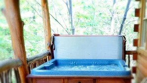 A wooden bench with a blue container in a wooden structure with a view of trees. - Cabin #6 - Laurel Haven (Stanardsville)