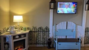 Una camera accogliente con televisione, un tavolo con lampada, una panca e un camino.