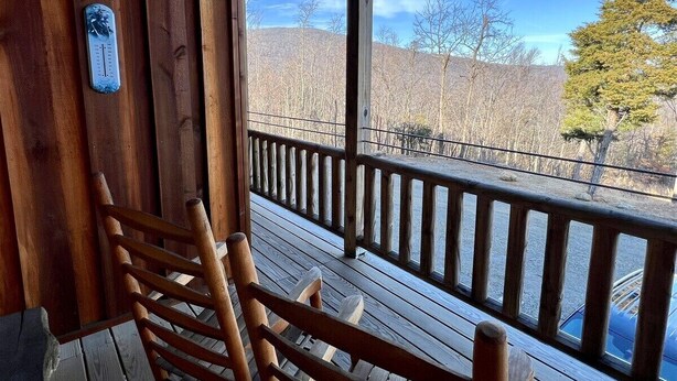 Un patio in legno con ringhiera, una sedia e un termometro appeso al muro.