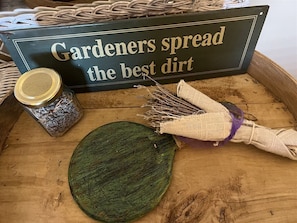 A wooden tray with a burlap sack, a jar of seeds, and a sign reading 'Gardeners spread the best dirt.' - Garden Oasis - Rm. 105 (Stanardsville)