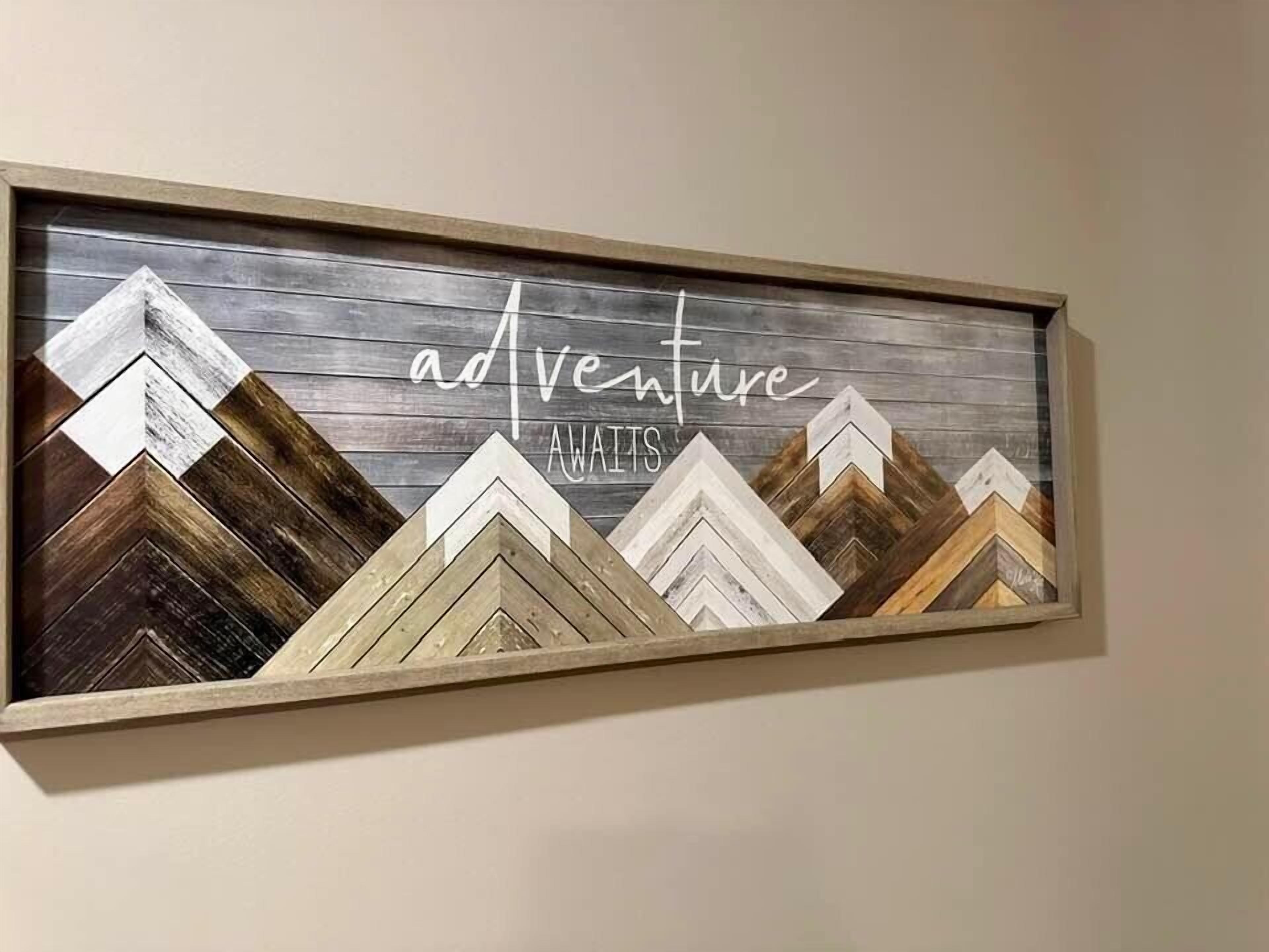 A framed artwork with the text 'adventure awaits' and a mountain-like design.
