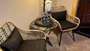 Two wicker chairs with dark cushions, a small round table with a lamp, and a sign on the table. - Wild & Free Room. 202 (Stanardsville)