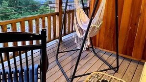 A wooden deck with a hammock, a chair, and a table. - Wild & Free Room. 202 (Stanardsville)