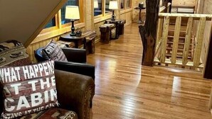 A cabin interior with a wooden floor, a sofa with a patterned cushion, a lamp, and a wooden structure resembling a tree. - Wild & Free Room. 202 (Stanardsville)