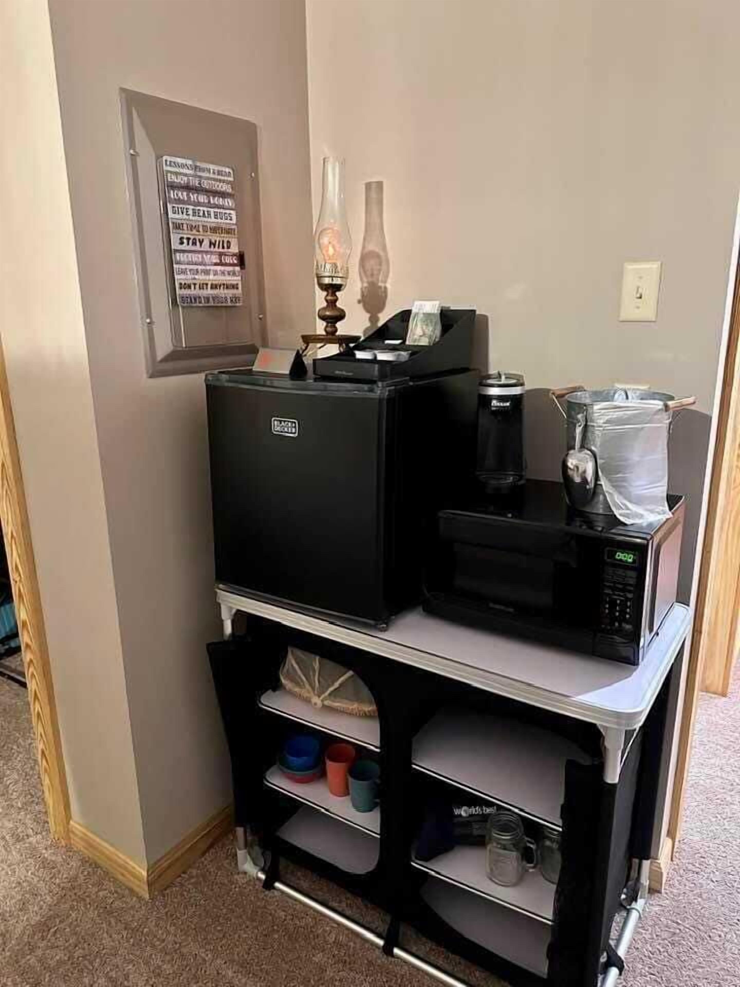A kitchenette with a coffee machine, a microwave, a small refrigerator, and a cabinet with kitchenware.