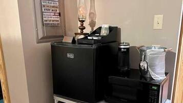 A kitchenette with a coffee machine, a microwave, a small refrigerator, and a cabinet with kitchenware.