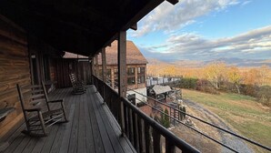 Une cabane en bois avec un porche, une vue sur une chaîne de montagnes et un ciel d égagé.