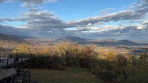 Un paysage montagneux avec une terrasse en bois et une vue sur des collines lointaines.