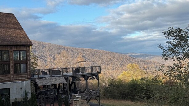 Un bâtiment rustique en bois, doté d’un balcon donnant sur un paysage montagneux.