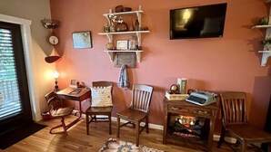 Un salon avec des meubles en bois, une cheminée, un téléviseur et des étagères ornées d’objets décoratifs.