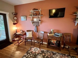 A living room with wooden furniture, a fireplace, a television, and shelves with decorative items. - Lydia Schoolhouse Rm. 112 (Stanardsville)