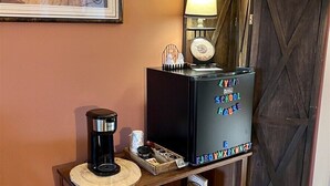 Une pièce comprenant une console en bois, une machine à café, un four à micro-ondes, un tableau encadré et un meuble orné d’une enseigne rappelant une école.