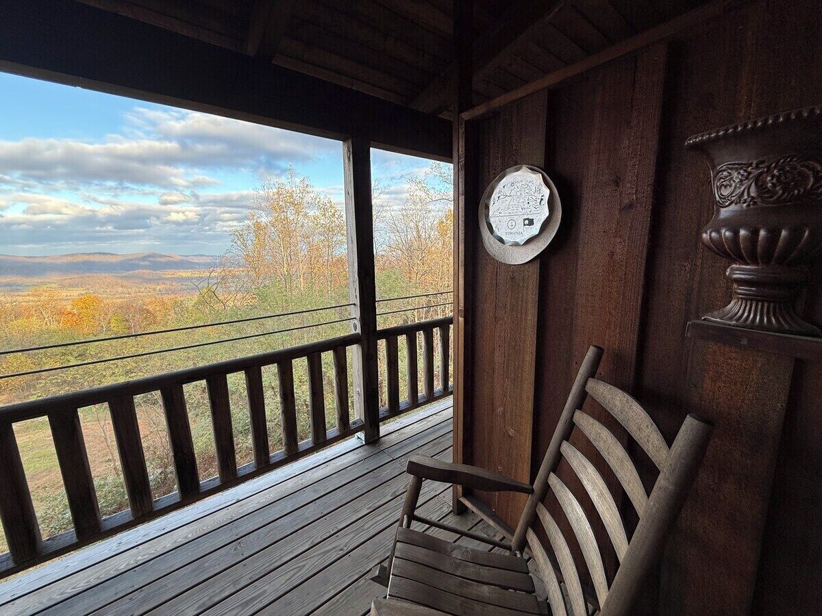 Un terrazza in legno con vista sul paesaggio, una sedia e una piastra decorativa fissata al muro.