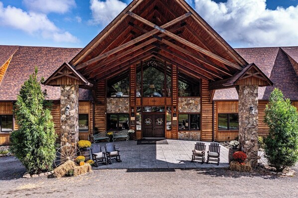Un bâtiment de style « cabane en rondins », doté de fondations en pierre, de grandes fenêtres et d’une entrée imposante.