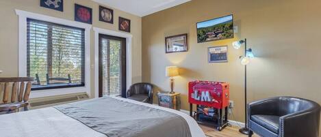 A hotel room with a bed, a chair, a desk, a lamp, and a window with blinds.