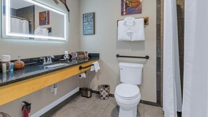 A bathroom with a large mirror, a toilet, a sink with a towel rack, and a shower curtain. - Lydia Legends Rm. 111 (Stanardsville)