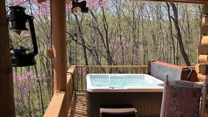 Eine Holzterrasse mit Whirlpool, einem Sessel und einer Laterne.