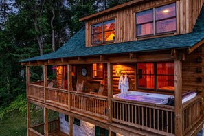 A log cabin with a balcony, a clock, and a hot tub.