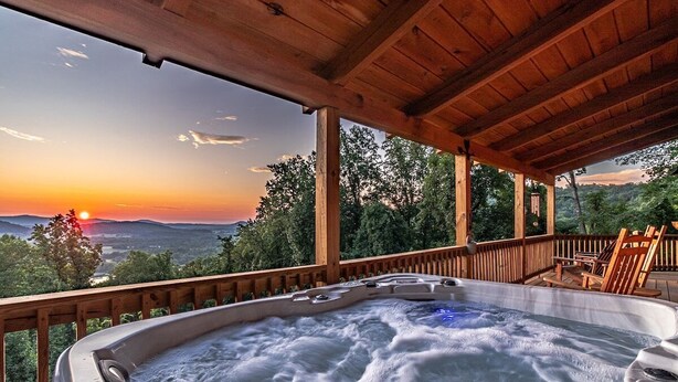 Un jacuzzi con terraza de madera y vista al atardecer.