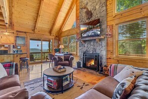 A log cabin interior with a fireplace, leather furniture, and a stone accent wall.