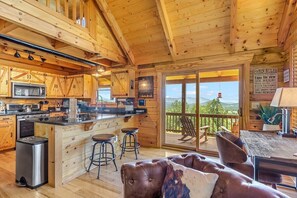 A cabin interior with a kitchen, bar area, and a balcony with a view.