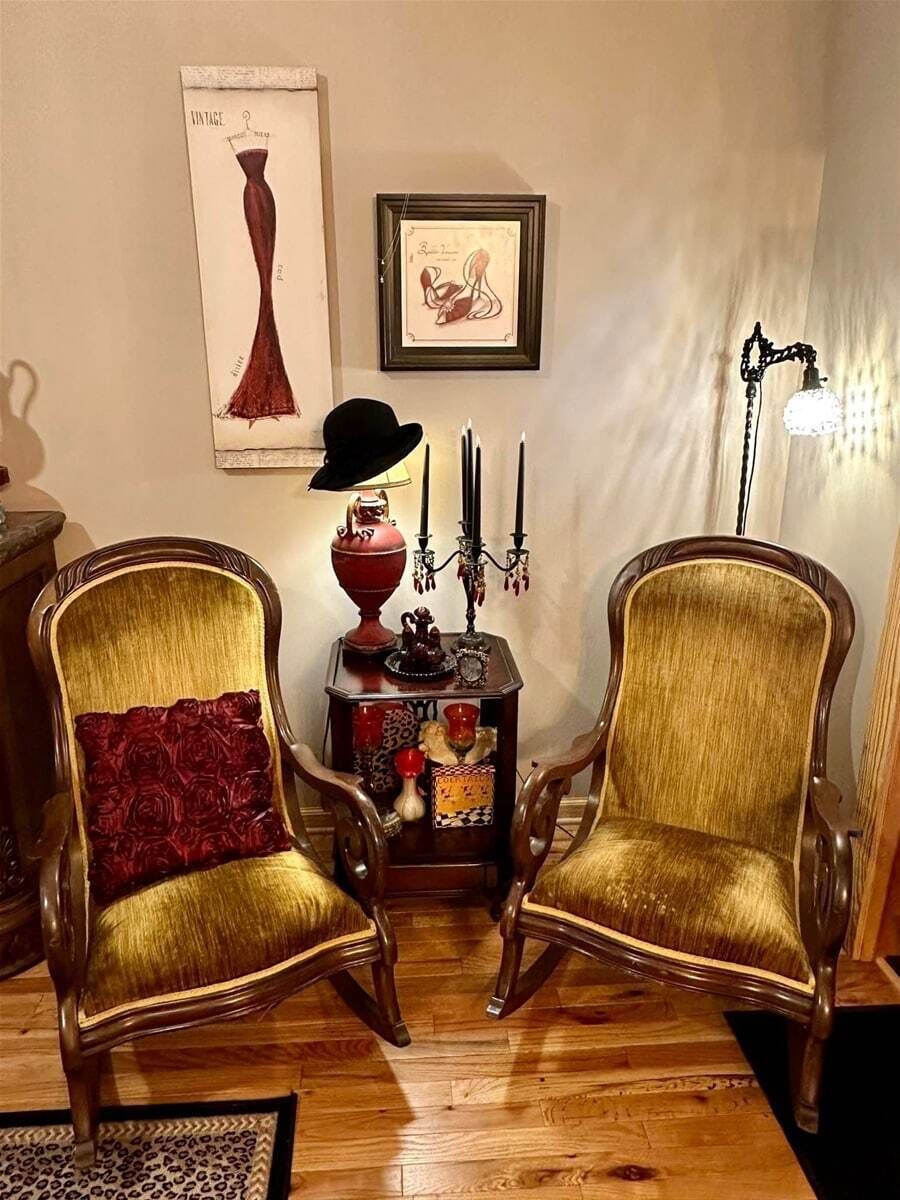 Two upholstered chairs with a decorative table between them, a framed picture on the wall, and a floor lamp.