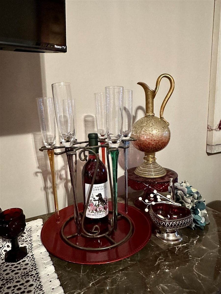 Une table avec une bouteille de vin rouge, un porte-verres décoratif et une lampe de style vintage.