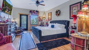 Une chambre à coucher avec un lit, un ventilateur de plafond, une commode, un téléviseur et une fenêtre.