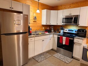 A kitchen with a stainless steel refrigerator, white cabinets, a microwave, and an oven.