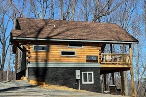 A log cabin with a balcony, a stone foundation, and a wooden deck. - Speckled Owl Mountain Cabin (Stanardsville)