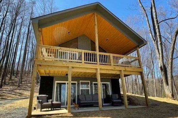 A two-story wooden cabin with a balcony, a covered porch, and a front door. - Speckled Owl Mountain Cabin (Stanardsville)