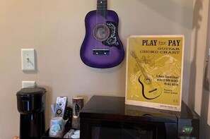 A purple guitar, a Play for Pay guitar chord chart, and a black electronic device on a table. - Music of the Mtns Rm. 203 (Stanardsville)