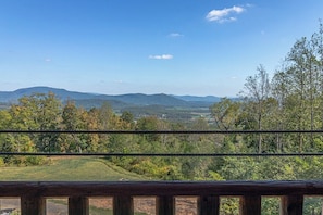 A view from a balcony with a wooden railing, overlooking a hilly landscape with trees and distant mountains. - Music of the Mtns Rm. 203 (Stanardsville)