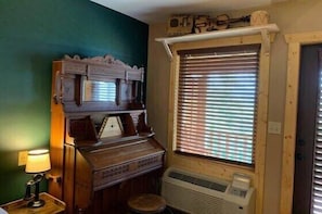Ein Zimmer mit Klavier, Heizkörper und einem Fenster mit Jalousien.